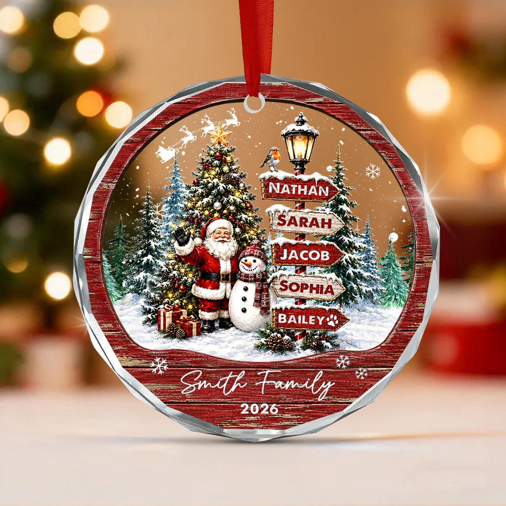 May include: A round, faceted Christmas ornament featuring a snowy scene with Santa Claus, a snowman, a decorated tree, and a street lamp with signs labeled Nathan, Sarah, Jacob, Sophia, and Bailey. The text Smith Family