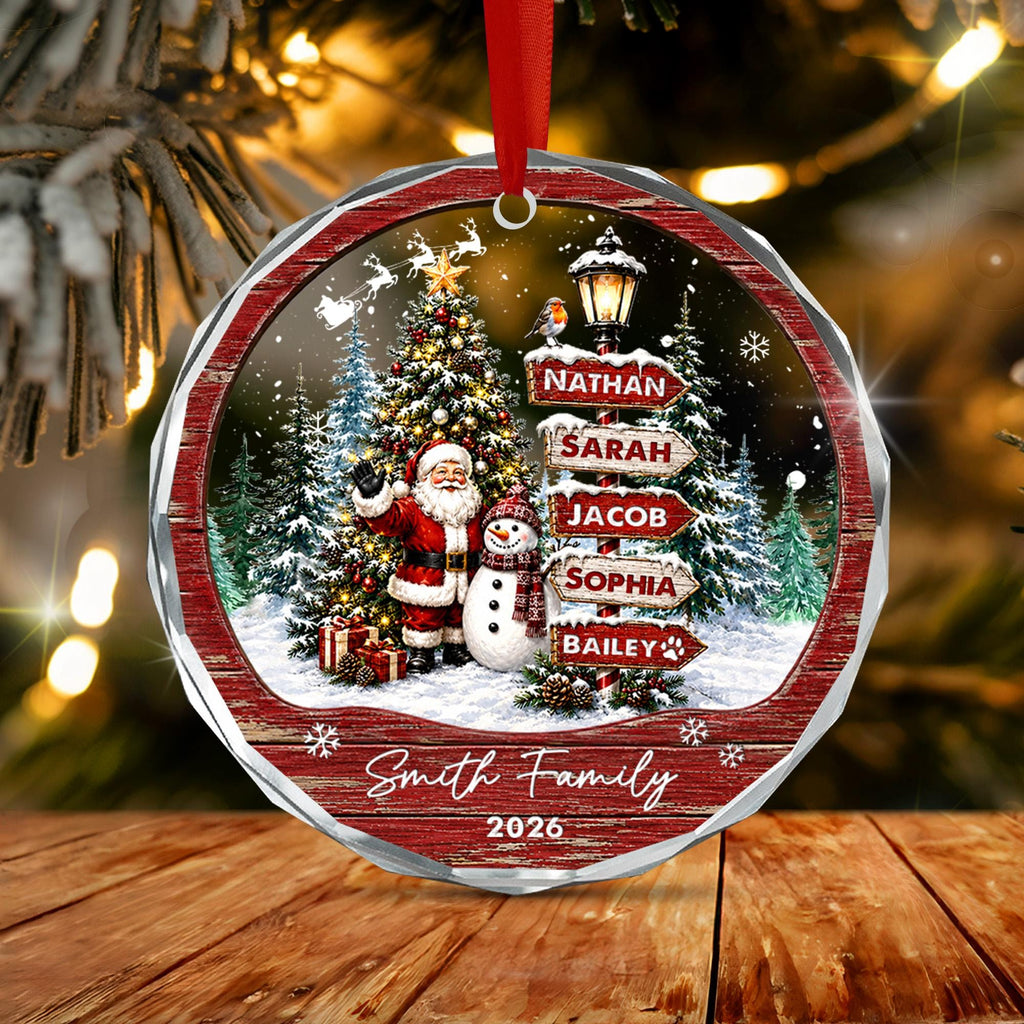 May include: A round, faceted Christmas ornament featuring a winter scene with Santa Claus, a snowman, a decorated tree, and a street sign listing the names Nathan, Sarah, Jacob, Sophia, and Bailey. The text Smith Family