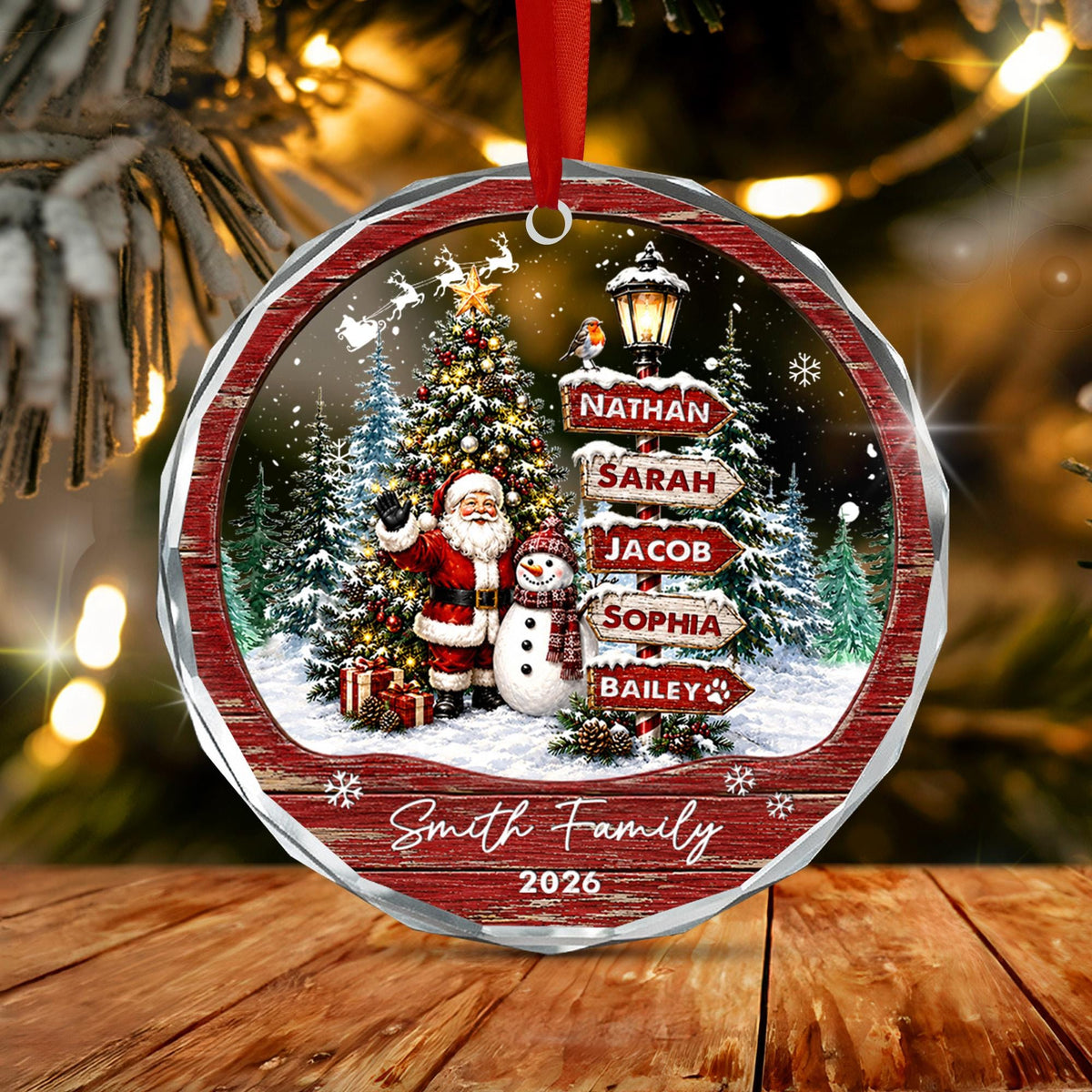 May include: A round, faceted Christmas ornament featuring a winter scene with Santa Claus, a snowman, a decorated tree, and a street sign listing the names Nathan, Sarah, Jacob, Sophia, and Bailey. The text Smith Family