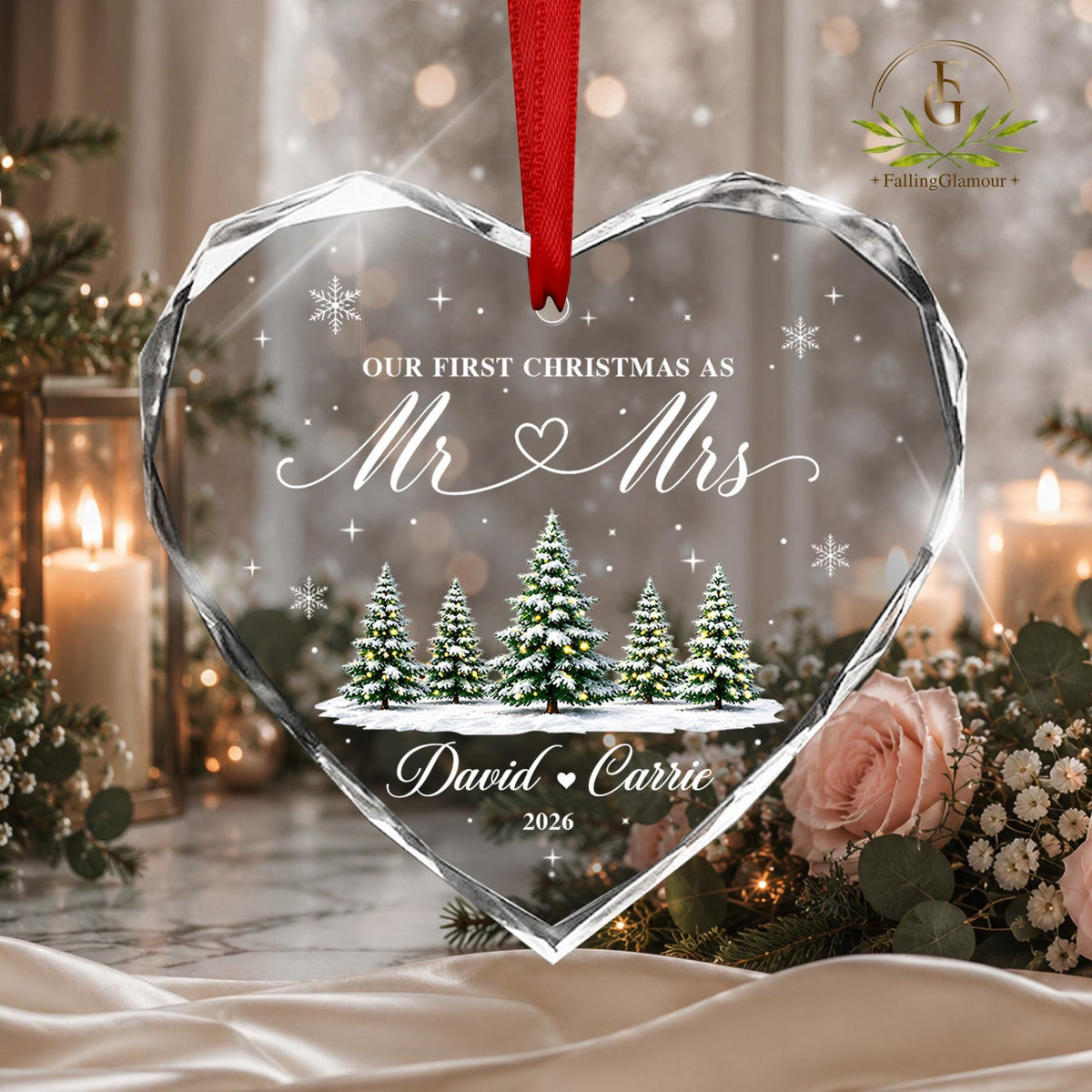May include: A heart-shaped clear glass ornament with faceted edges, hanging from a red ribbon. It features the text "OUR FIRST CHRISTMAS AS Mr &amp; Mrs", "David &amp; Carrie", and "2026" a